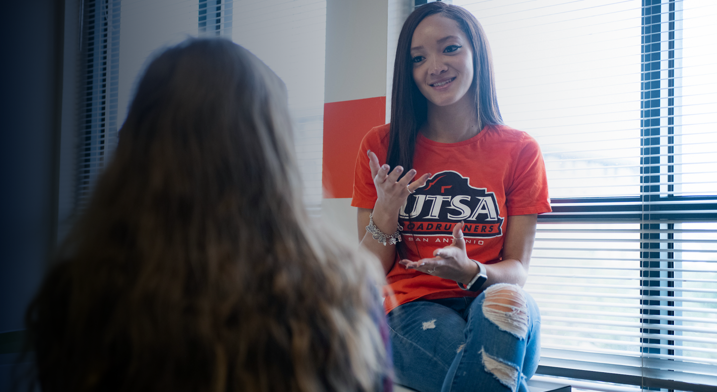Two students talking next to a window